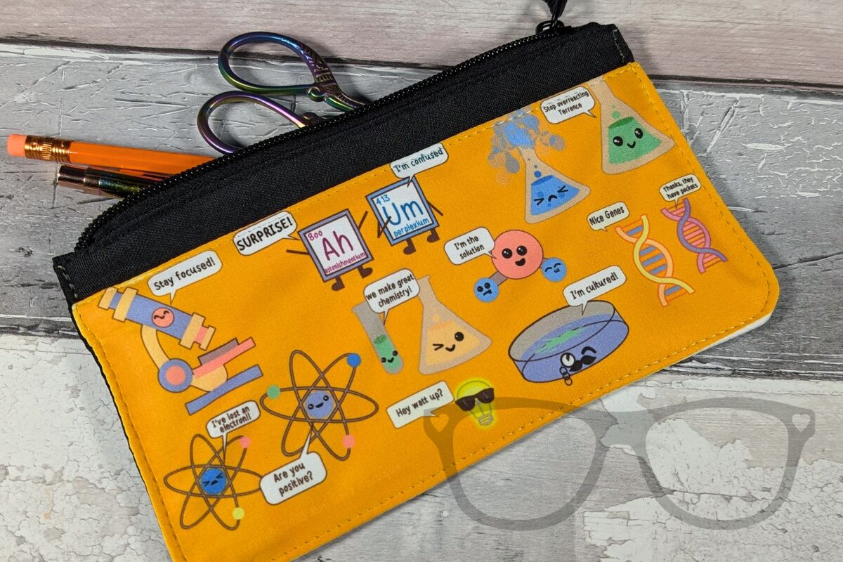 An orange pencil case with lots of science puns, with some contents spilling out