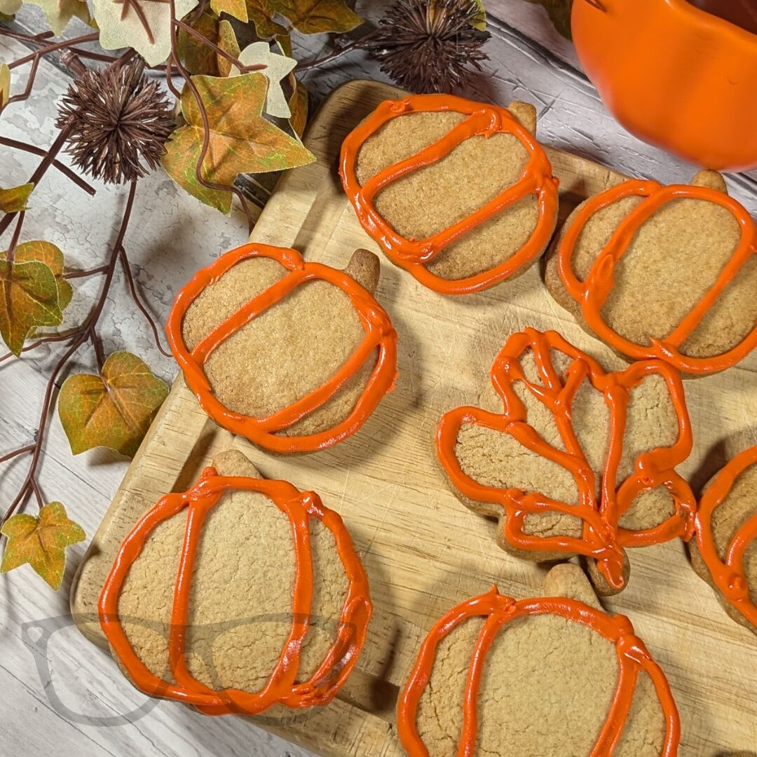 A wooden board with several pumpkin shaped cookies